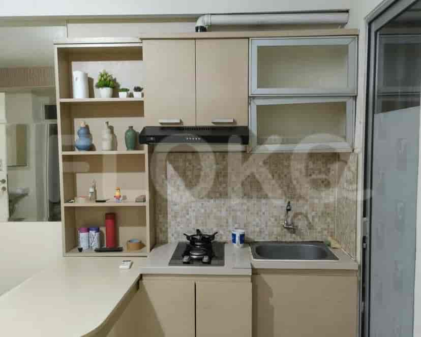 Tampilan dekat dapur dengan lemari kayu, kompor gas, dan backsplash ubin.
