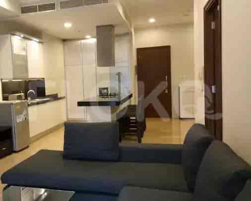 A modern apartment with an open-plan kitchen, a dark grey sofa, and a view of the dining area.