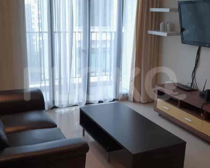 Living room with a black sofa, coffee table, TV unit, and large windows with curtains.