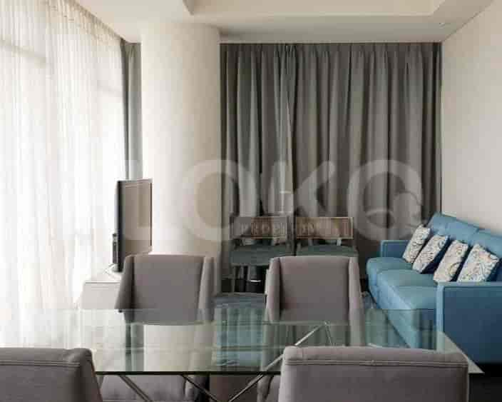 A living room with a glass table, blue sofa and curtains.