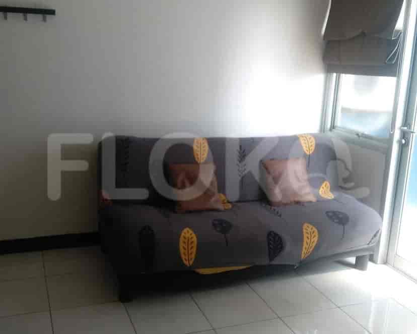 A small living area with a grey sofa and simple decor.
