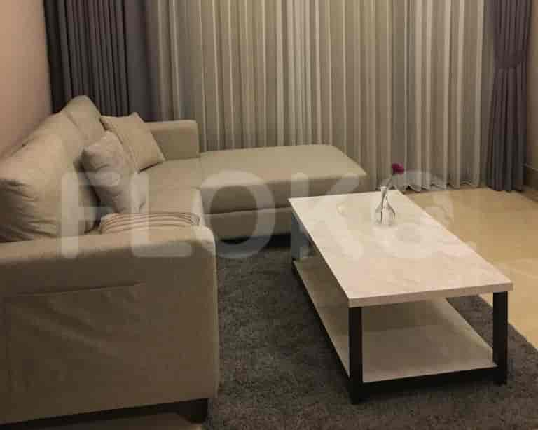 A living room with a beige L-shaped sofa, a coffee table, and curtains.