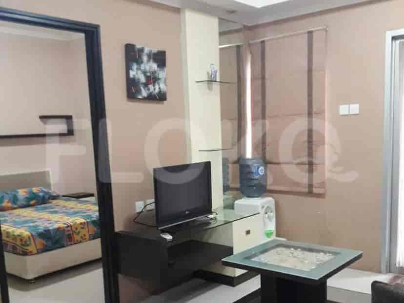 A room with a bed and seating area, featuring a TV, water dispenser, and abstract art.