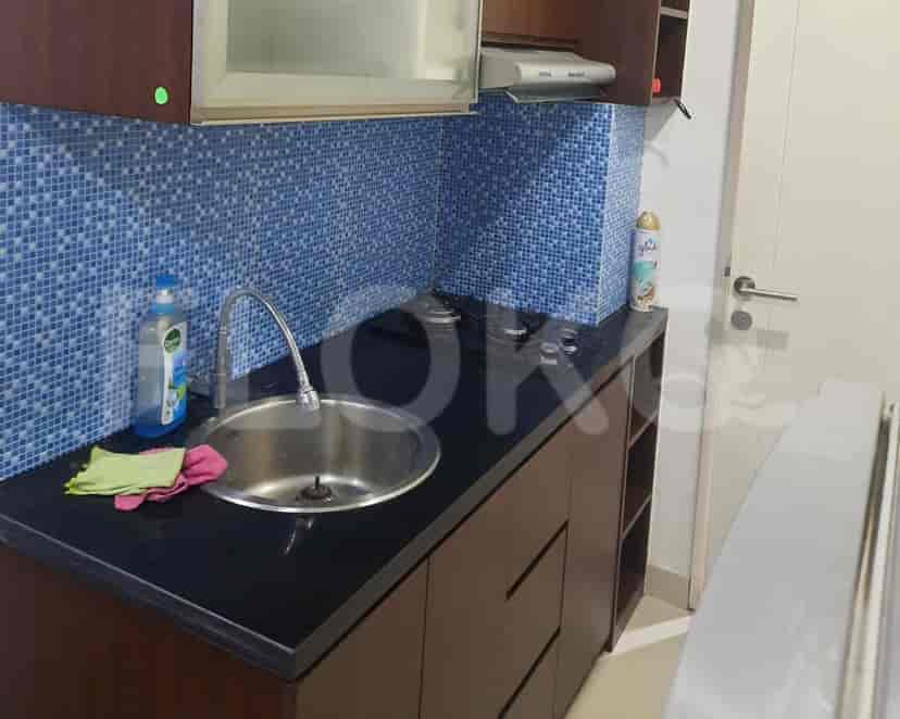 A modern kitchen with dark countertops, blue tiled backsplash, and stainless steel sink.