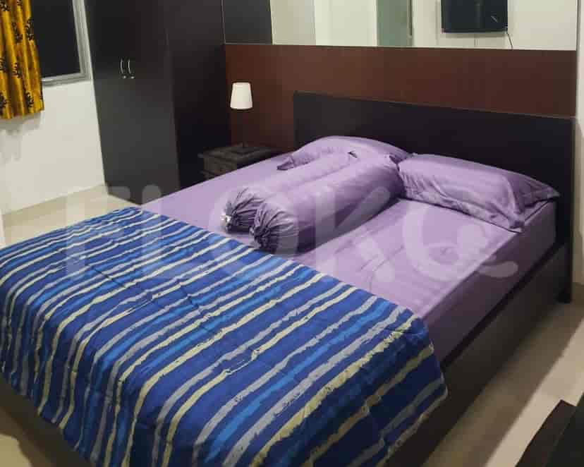 A bedroom featuring a bed with purple bedding, a wooden headboard, and a wardrobe.