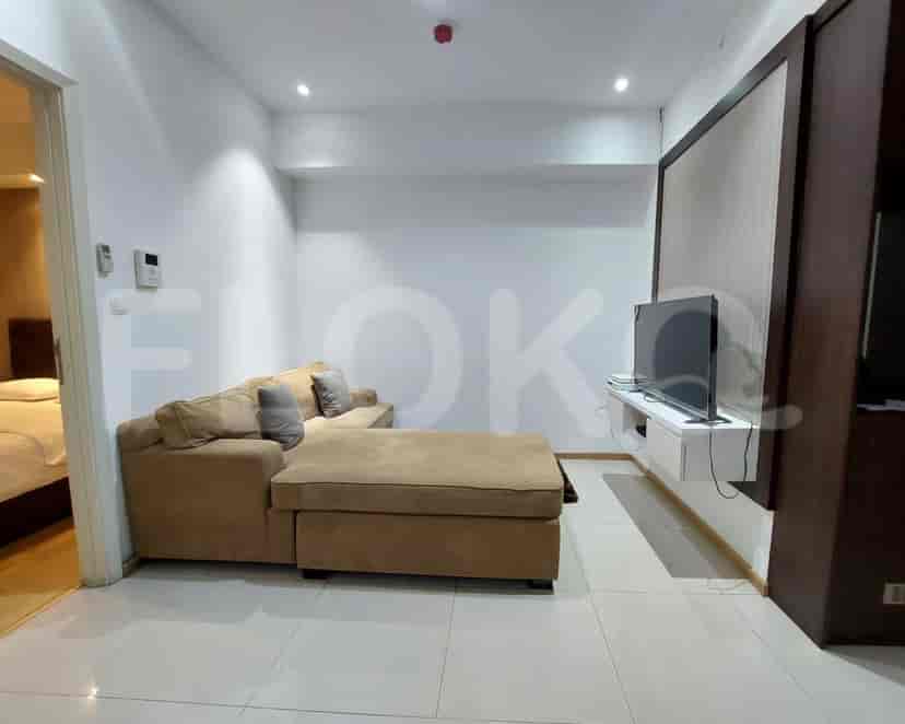 A modern living room featuring a sectional sofa, TV, and an open doorway to the bedroom.