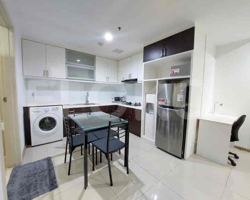 A well-equipped kitchen with a dining table, washing machine, and stainless steel refrigerator.