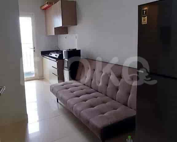 A kitchenette area with a futon sofa, refrigerator, and a kitchenette area.