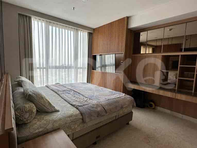 A bedroom with a large bed, wall-mounted TV, and expansive windows.