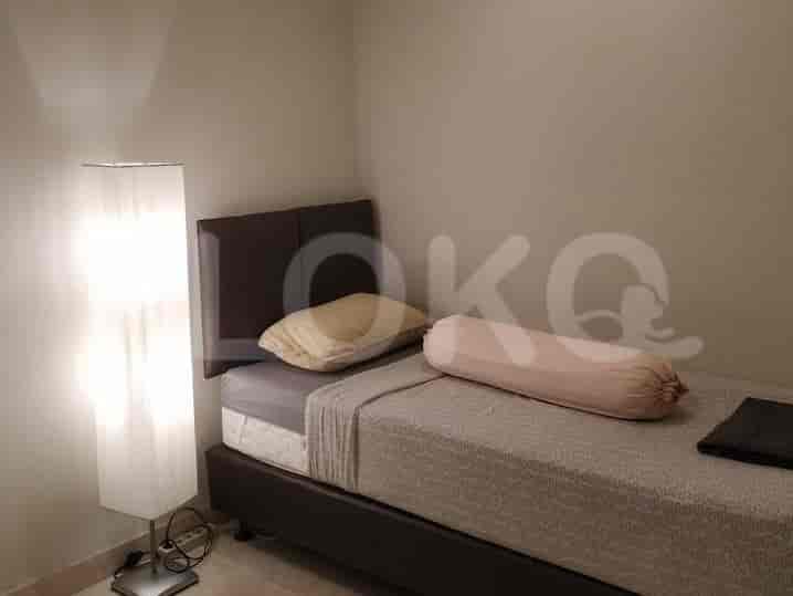 A small bedroom with a single bed and a floor lamp.