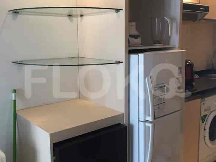 A small kitchen with a refrigerator, overhead cabinets, and glass shelves.
