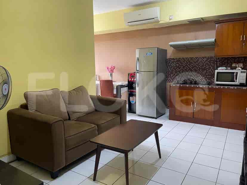 A living room and kitchen with a sofa, table, and refrigerator.