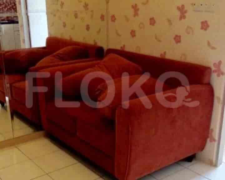 A living room with a red sofa and floral wallpaper.
