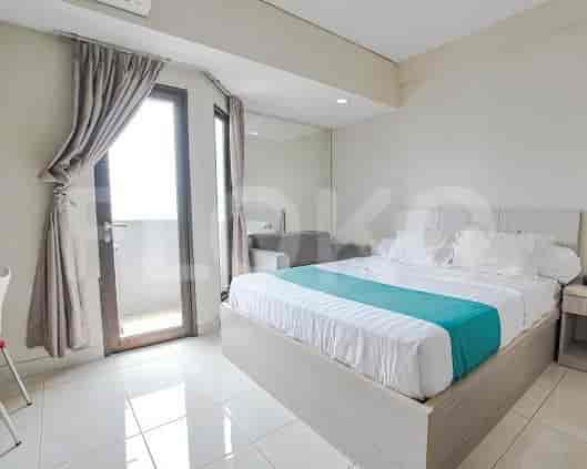 A bedroom with a bed, a large window, and curtains.