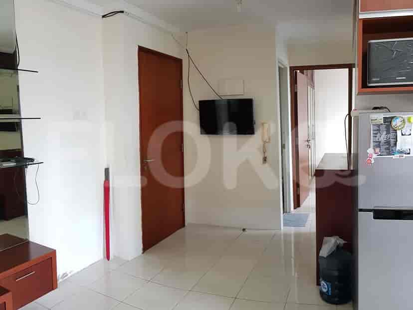 Entryway with tiled floor, a wall-mounted TV, and doors leading to other rooms.