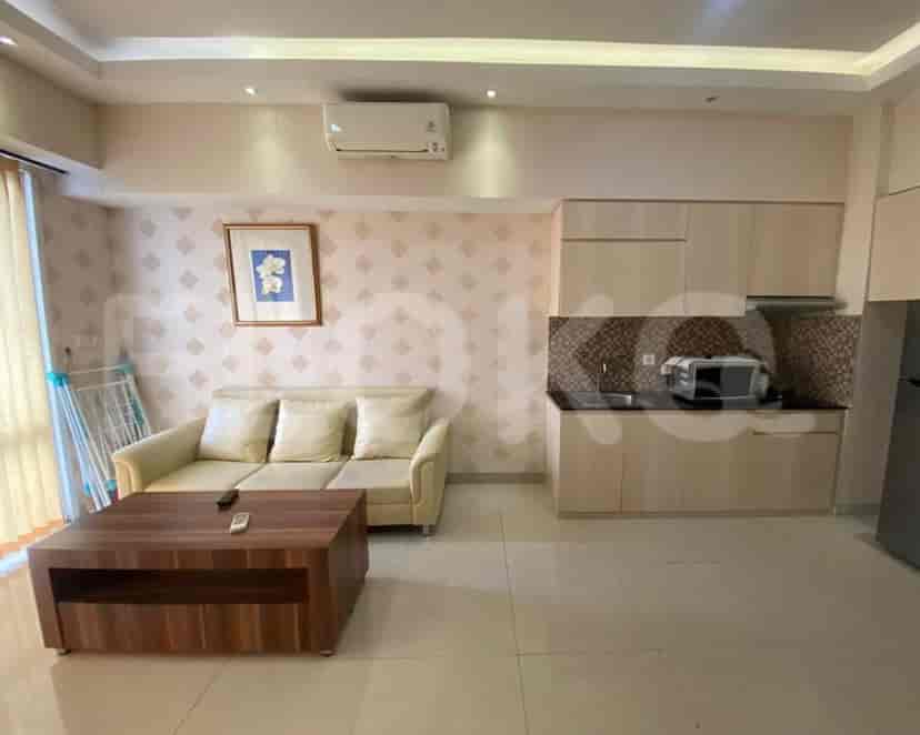 Combined living room and kitchen area with sofa, kitchen cabinets, and dining area.