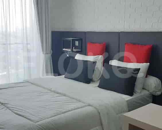 A modern bedroom featuring a double bed with decorative pillows and a small shelf above.