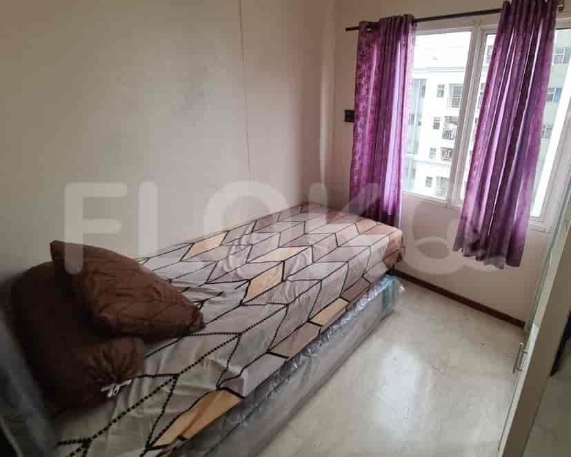 A small bedroom with a single bed and window with purple curtains.