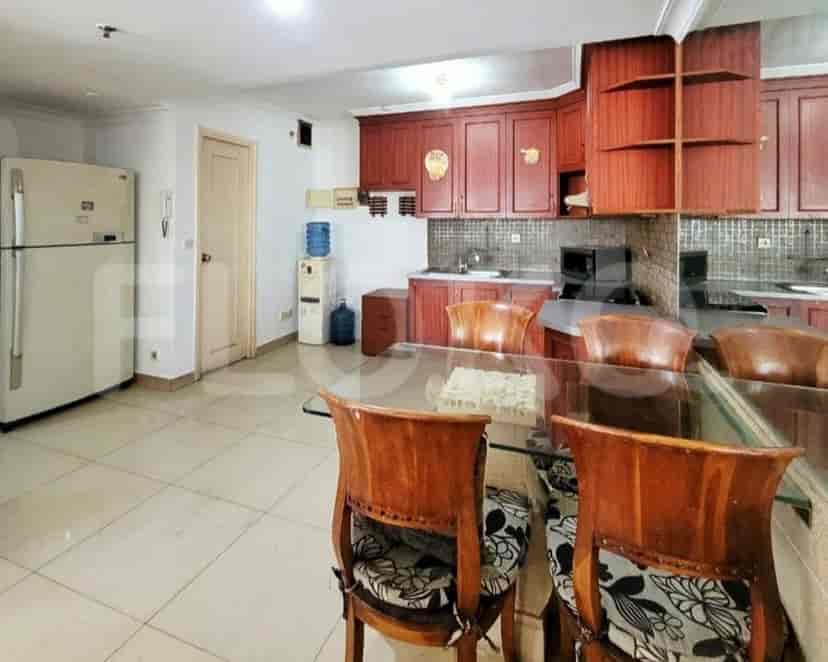 A well-lit kitchen and dining area with wooden cabinets and a glass-top dining table.