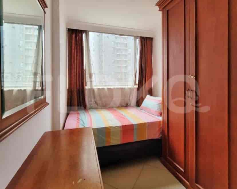 A small bedroom with a single bed, a wardrobe, and a window.