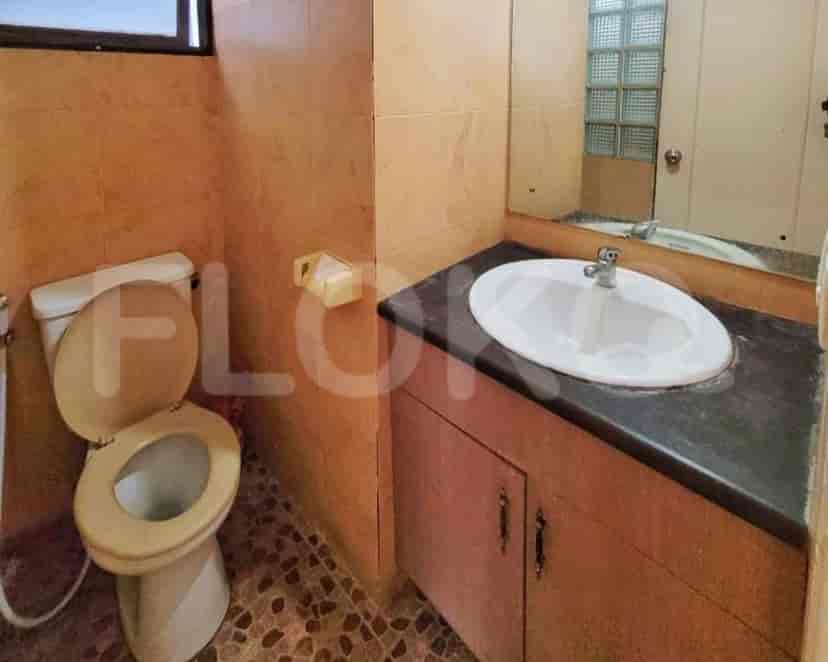 A bathroom with a toilet, a sink, and beige tiles.