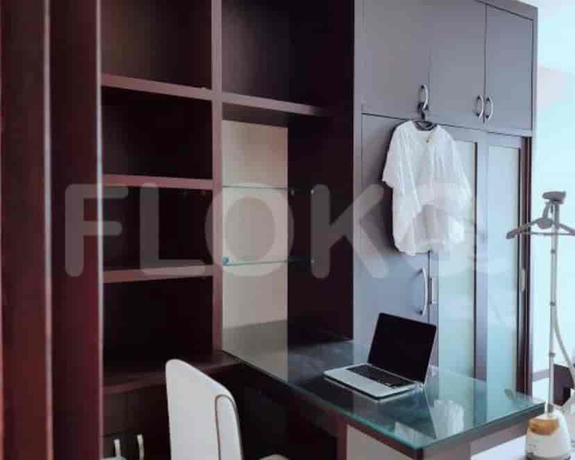 Sebuah kantor rumah dengan meja, rak terbuka, dan laptop.