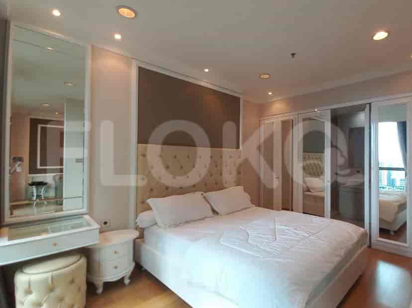 A master bedroom with a large bed, vanity, and mirrored closet.