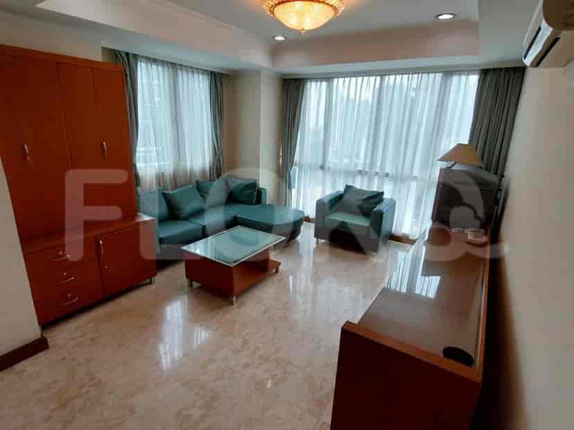 A living room with a green sofa, a coffee table, and large windows with curtains.