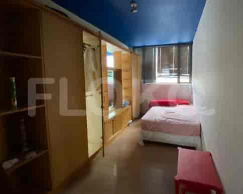 A small bedroom with a bed, red side table, and a large closet.
