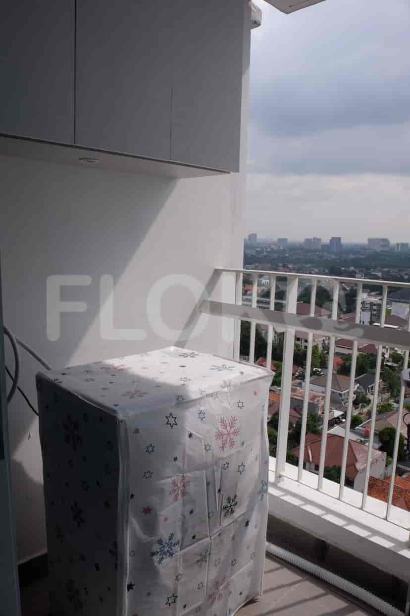 A balcony with a view of the city and an appliance, likely an AC unit.