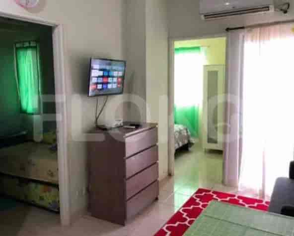 A living room with a TV, cabinet, and doorway to a bedroom.