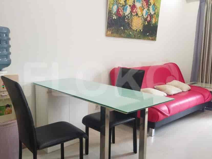 Dining area with a glass table, black chairs, and a red sofa.