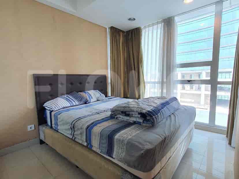 A bedroom with a queen-sized bed, floor-to-ceiling windows, and beige walls.