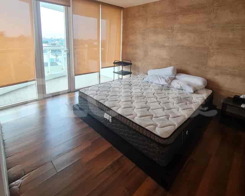Kamar tidur dengan tempat tidur besar, lantai kayu, dan jendela setinggi langit-langit.