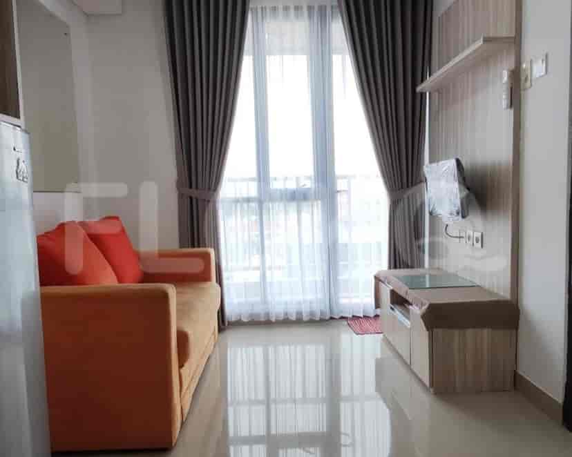 Ruang tamu dengan sofa oranye, jendela dengan gorden, dan TV.
