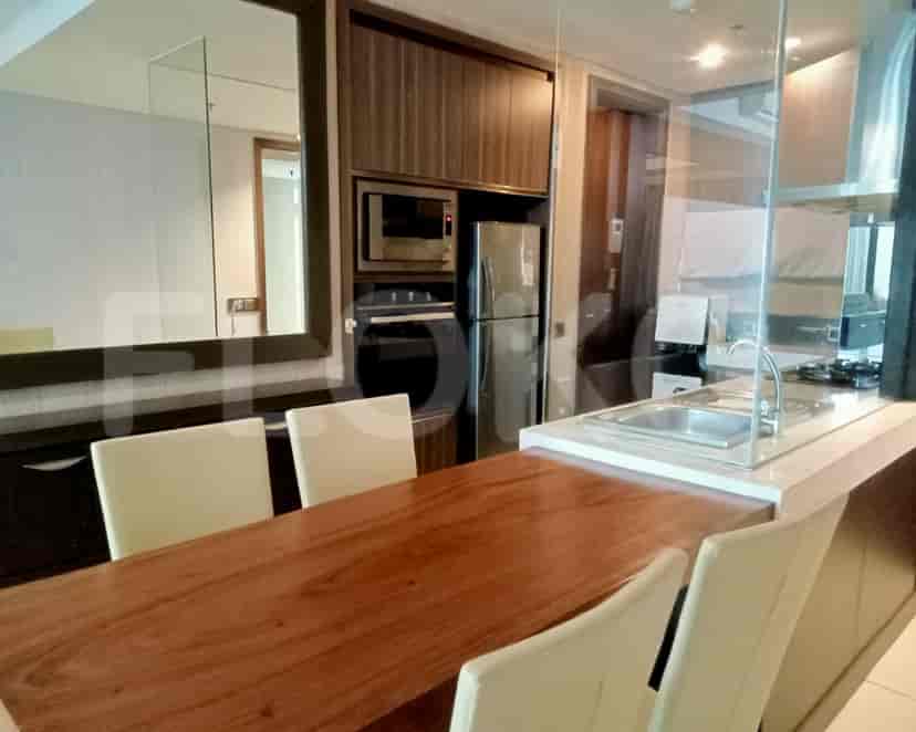 A modern kitchen with a dining table, built-in appliances, and a glass divider.