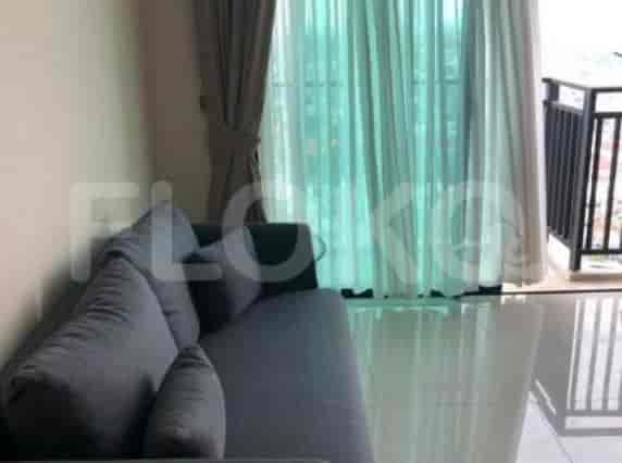 Ruang tamu dengan sofa abu-abu dan jendela besar.