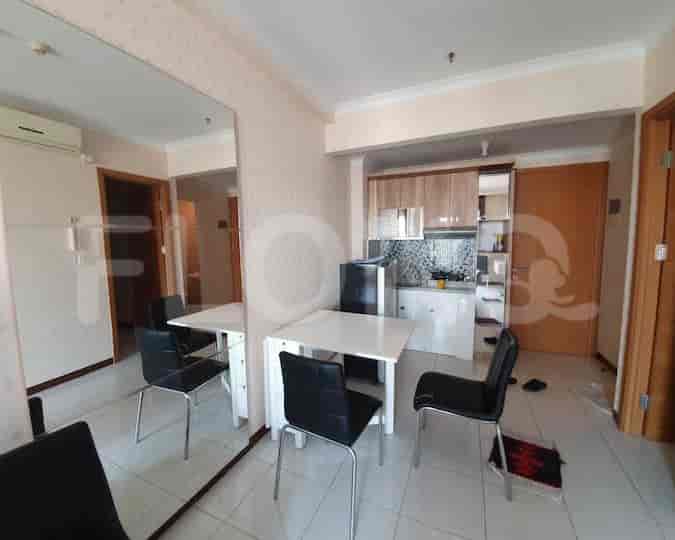 A dining area and a small kitchen with a fridge.