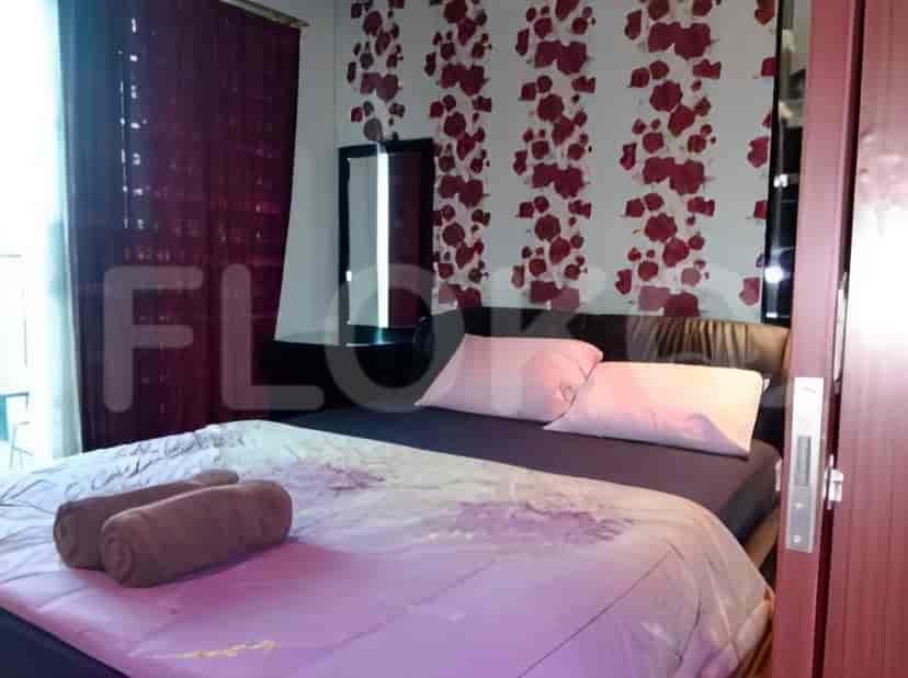 Kamar tidur yang nyaman dengan tempat tidur berisi bantal dan handuk, di samping cermin dan hiasan dinding.