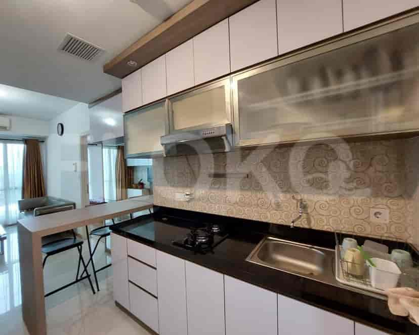 A modern kitchen with light wood cabinets, black countertops, and stainless steel appliances.