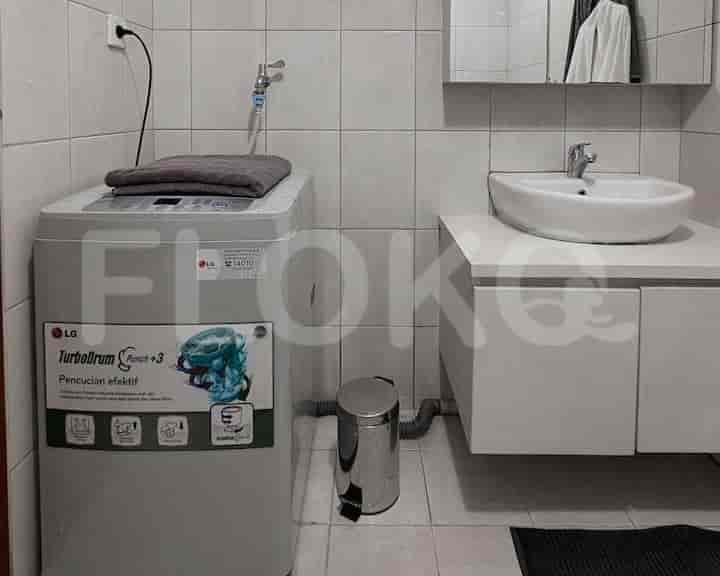 A compact bathroom featuring a washing machine, sink, and a mirrored cabinet.