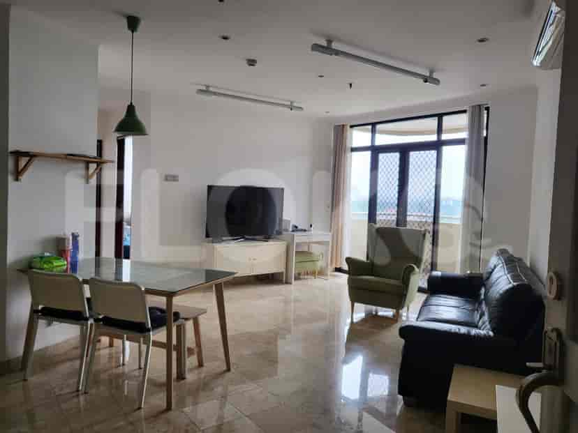 A well-lit living room and dining area with a glass-top dining table, a leather sofa, and a TV cabinet.