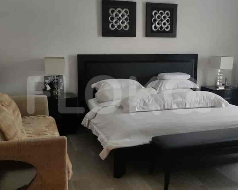 Kamar tidur modern dengan rangka tempat tidur hitam, linen putih, dan meja samping tempat tidur.