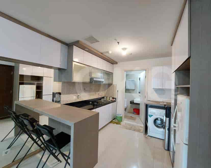 A modern kitchen with white cabinets, a breakfast bar, and a washing machine.