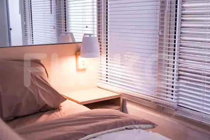 A close-up of the bed area, featuring a lamp and a nightstand.