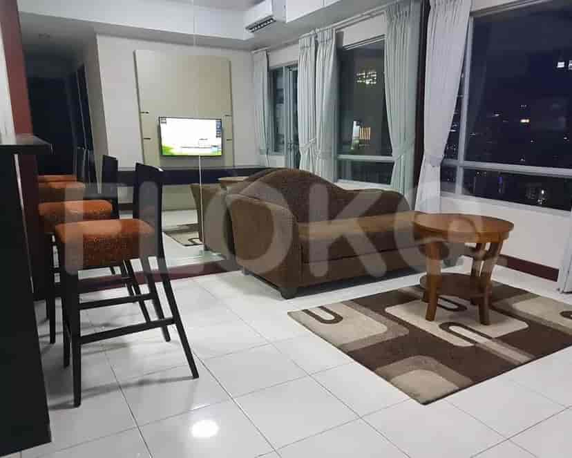 A well-lit living room featuring a brown sofa, wooden stools, and city view.
