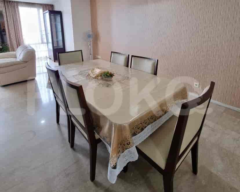 A dining room with a rectangular dining table, six chairs, and a patterned tablecloth.