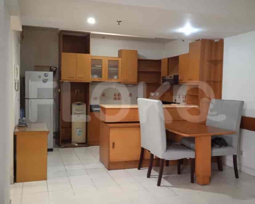 Kitchen with wooden cabinets, fridge, and a dining table.