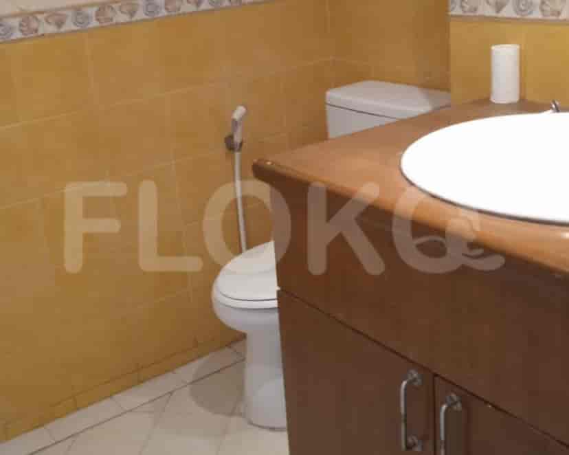 Bathroom with a toilet, sink, and wall tiles.