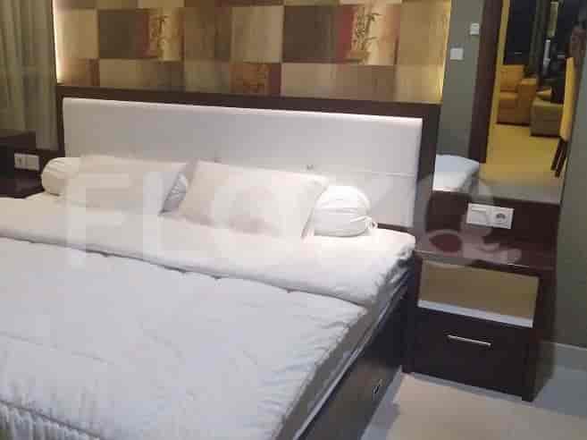 A bedroom with a large bed, a nightstand, and a mirror.